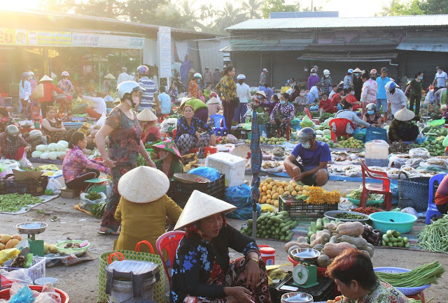 People squat in a local market in Vietnam